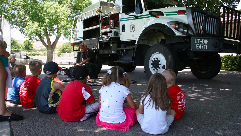Children listening to speaker in front of truck